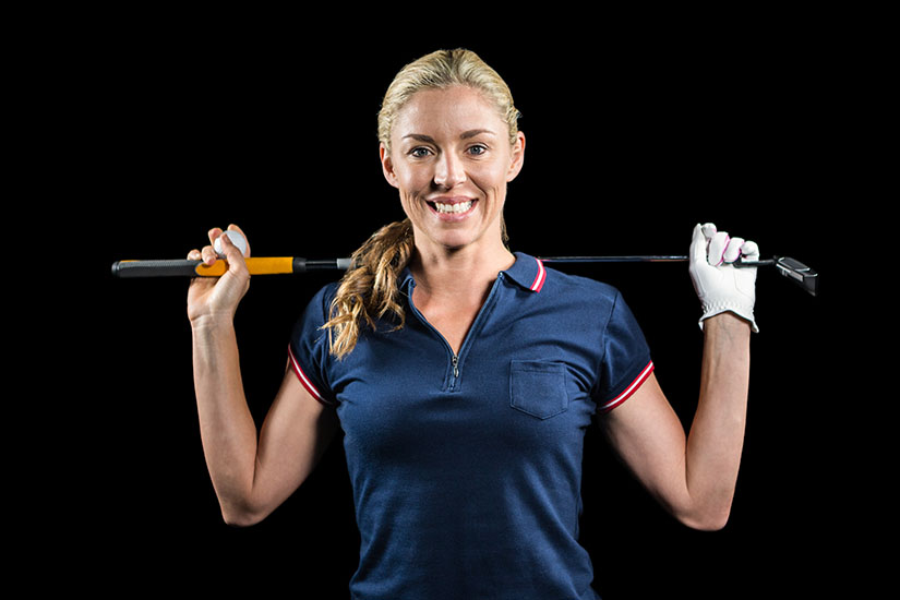 Portrait of golf player holding a golf club on black background